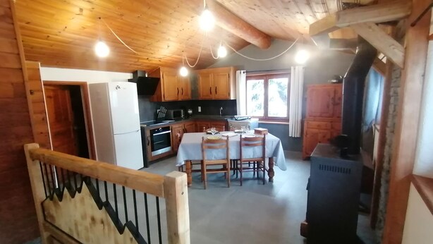 A cozy cabin-style kitchen with wooden cabinets, a dining table, and a wood-burning stove. - Maisonnette 4/5 persons in Saint-Véran 2*. (Saint-Véran)