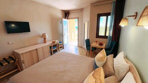 A hotel room with a large bed, a desk with a chair, a television, and a window with curtains. - Mangrove Bay Resort (El Quseir)