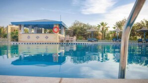 A swimming pool with a blue-roofed structure and lounge chairs in the background. - Mangrove Bay Resort (El Quseir)