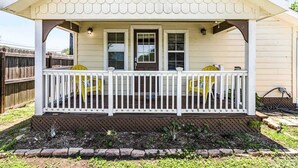 Eenlaags huis met een veranda, een voordeur en een kleine tuin.