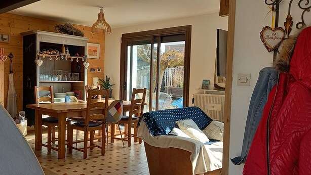 A cozy dining area with a wooden table and chairs, a cabinet with glassware, and a view of the outdoors through a sliding glass door. - Charming, quiet town house with small garden  (Crest)