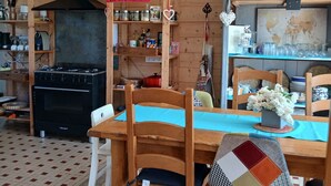 A wooden interior with a kitchen area, a dining table with chairs, and a hanging light fixture. - Charming, quiet town house with small garden  (Crest)
