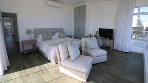 Ein modernes Hotelzimmer mit einem großen Bett, einer Couch, einem Fernseher und einem Kleiderschrank.