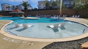 A swimming pool with lounge chairs, a no diving sign, and a palm tree. - New Heated Pool & Hot tub! Adorable Condo! (Galveston)
