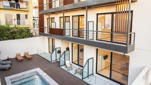 Ein modernes Gebäude mit Pool auf dem Dach, Außenbereich zum Sitzen und großen Fenstern.