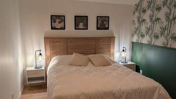 Une chambre avec un lit en bois, un puits de lumière et un mur décoré d’un motif en bambou.