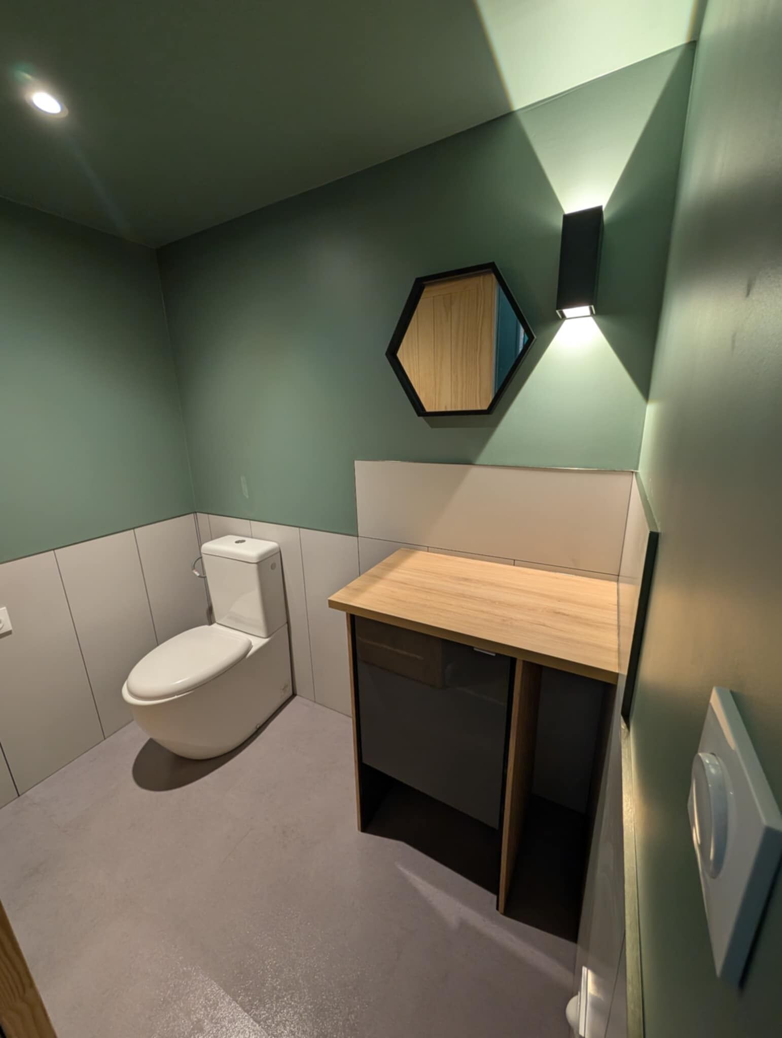 Ein kleines Badezimmer mit Toilette, einem Holztischchen und einem Spiegel an der Wand.