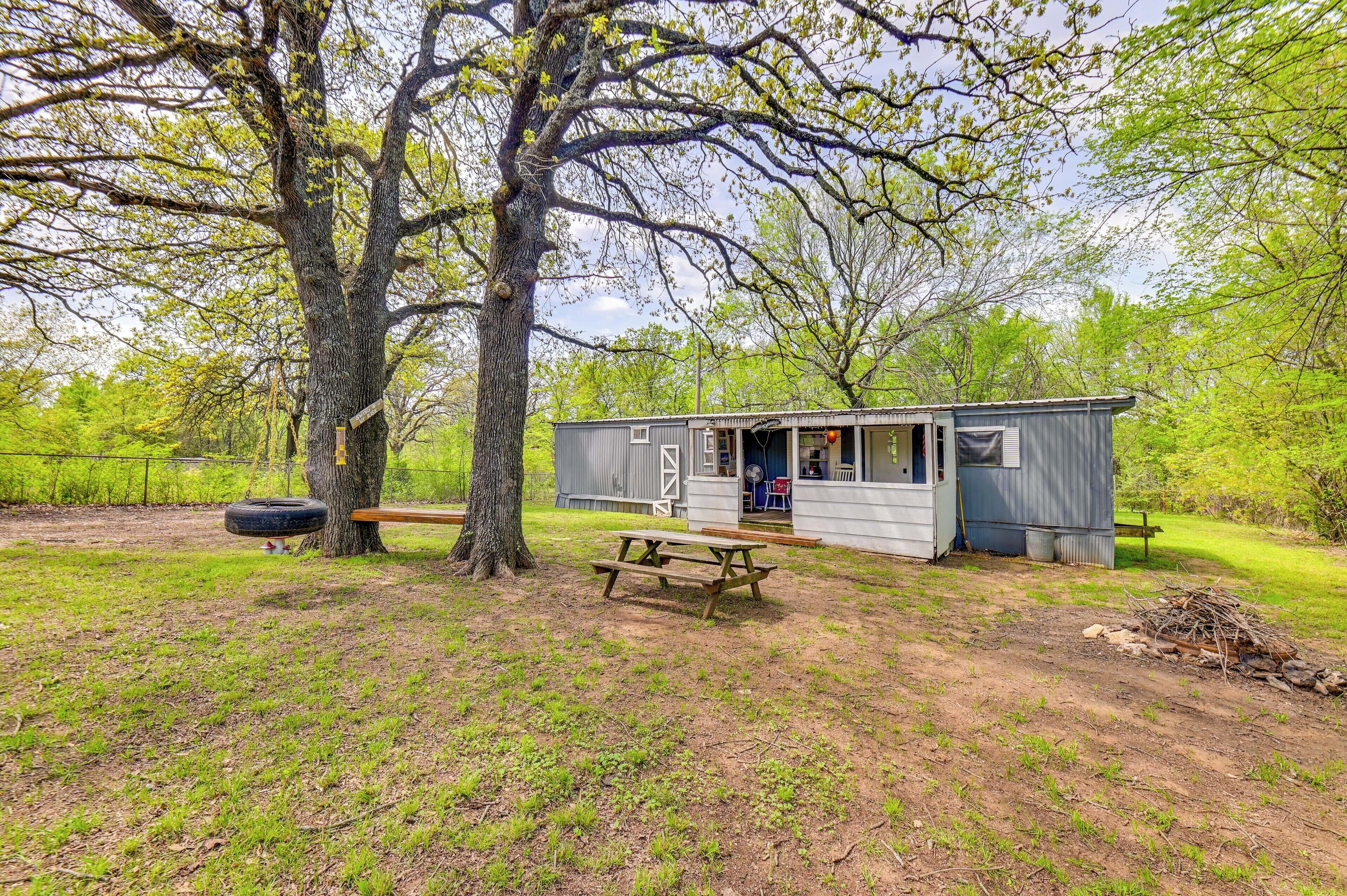 A rustic cabin with a wooden deck, a picnic table, and a tire swing.