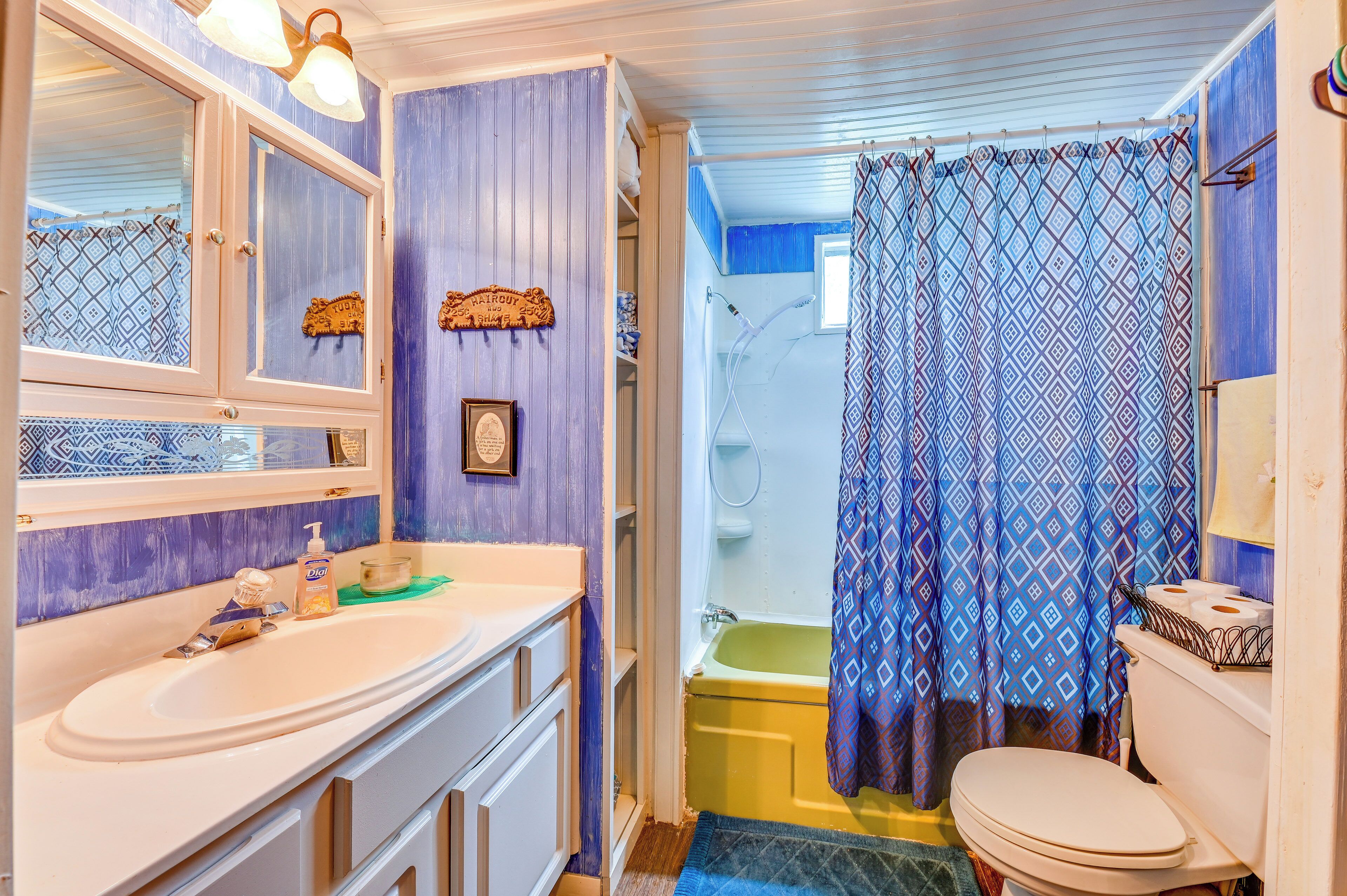A bathroom with a white sink, mirror, and toilet. There is a shower curtain with a geometric pattern.