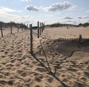 A sandy beach with wooden fencing and a rope barrier.