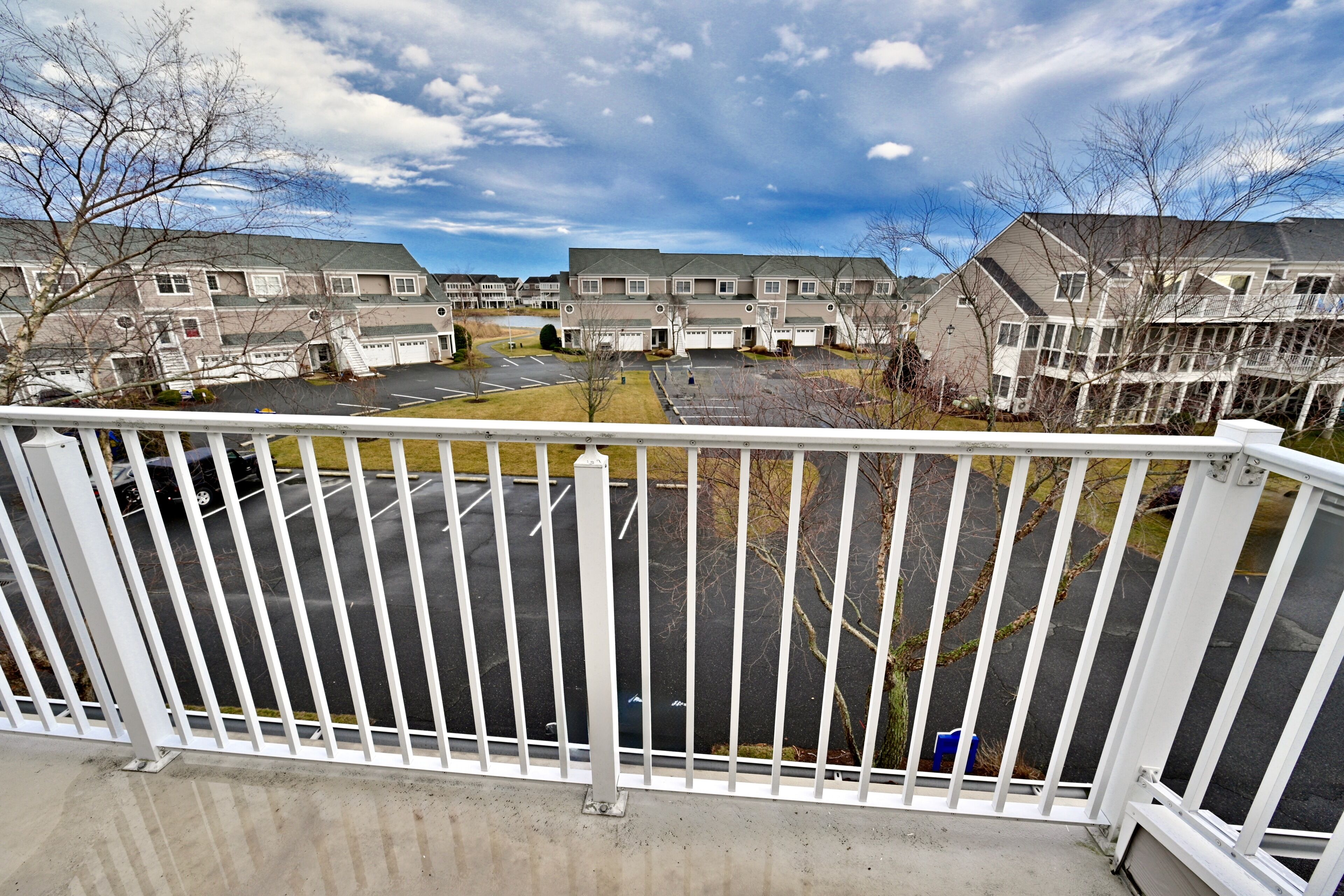 En bostadsbyggnad med flera garage, en parkeringsplats och en balkong med ett vitt räcke.