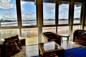 A room with a large window, a sofa, a chair, and a small table.