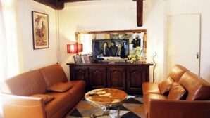 A living room with two brown leather sofas, a coffee table, and a television on a wooden cabinet.