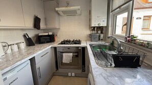 Een kleine keuken met een inbouwoven, magnetron en spoelbak.