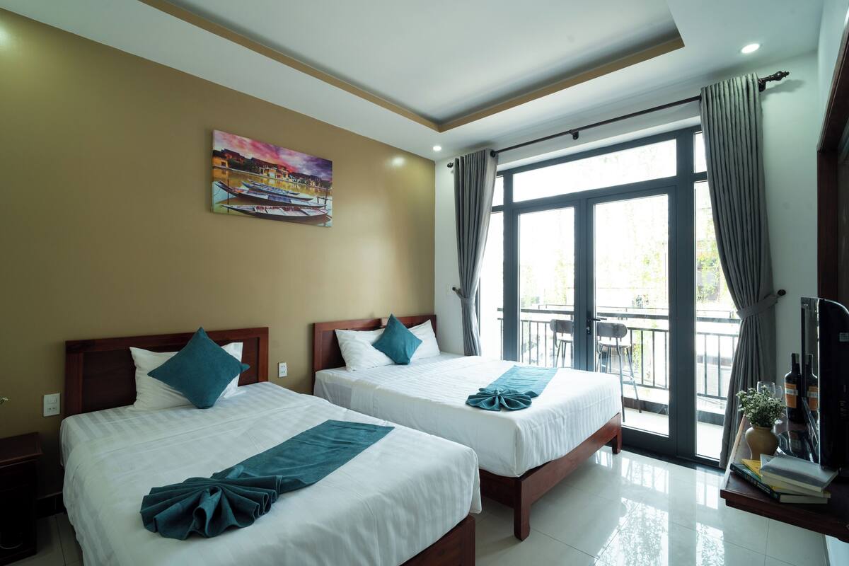 A hotel room with two beds, a balcony, and a painting on the wall.
