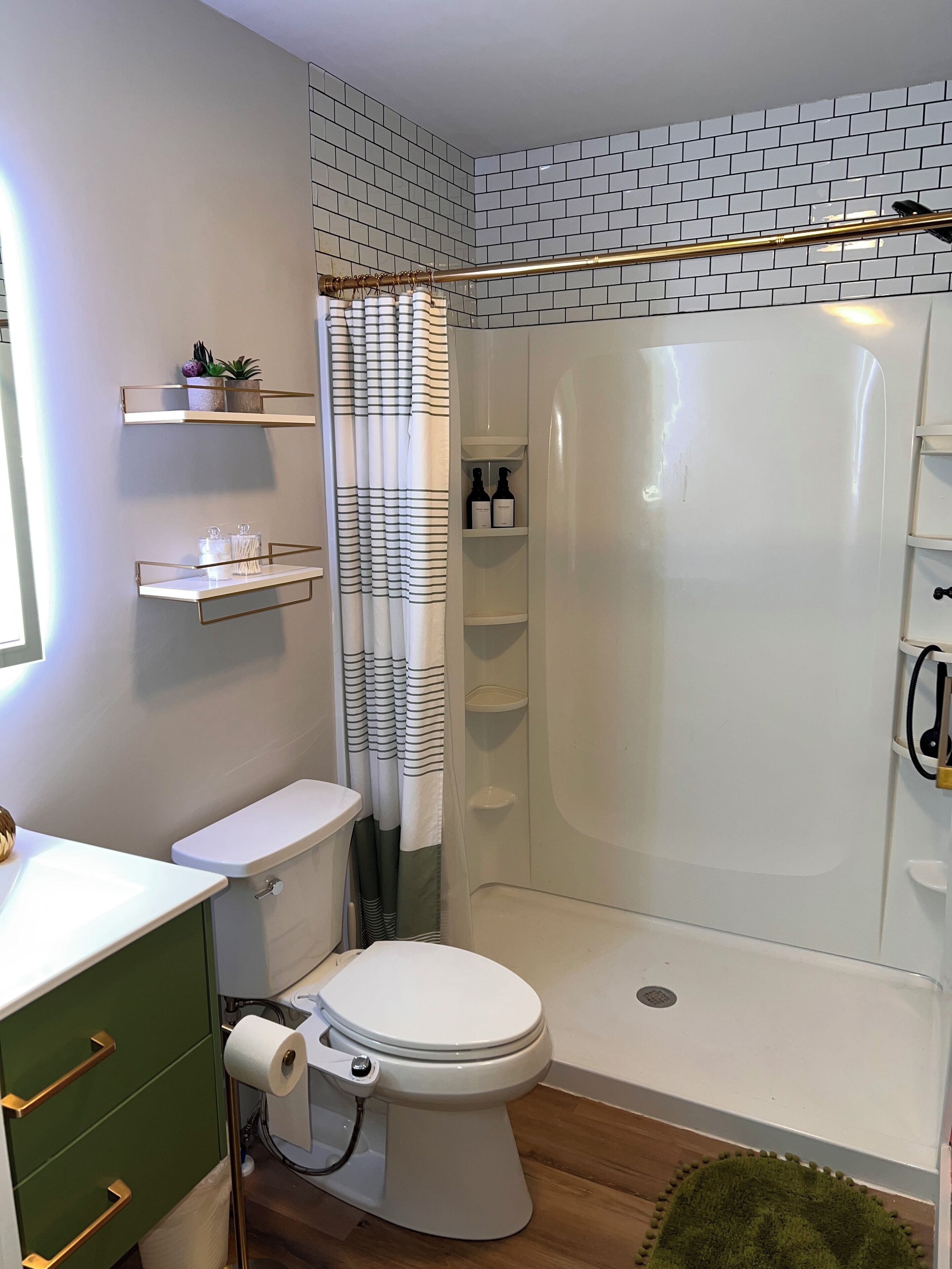 Une salle de bain moderne équipée de toilettes, d’une douche et d’étagères où sont rangés les produits de toilette.