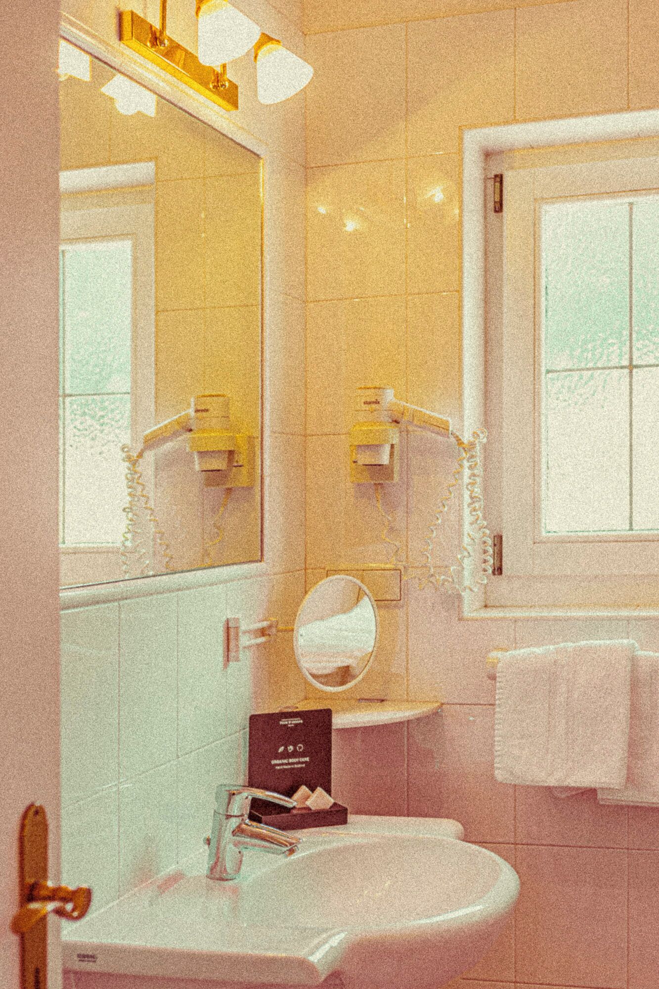 Un baño con lavamanos, espejo y perchero para toallas.