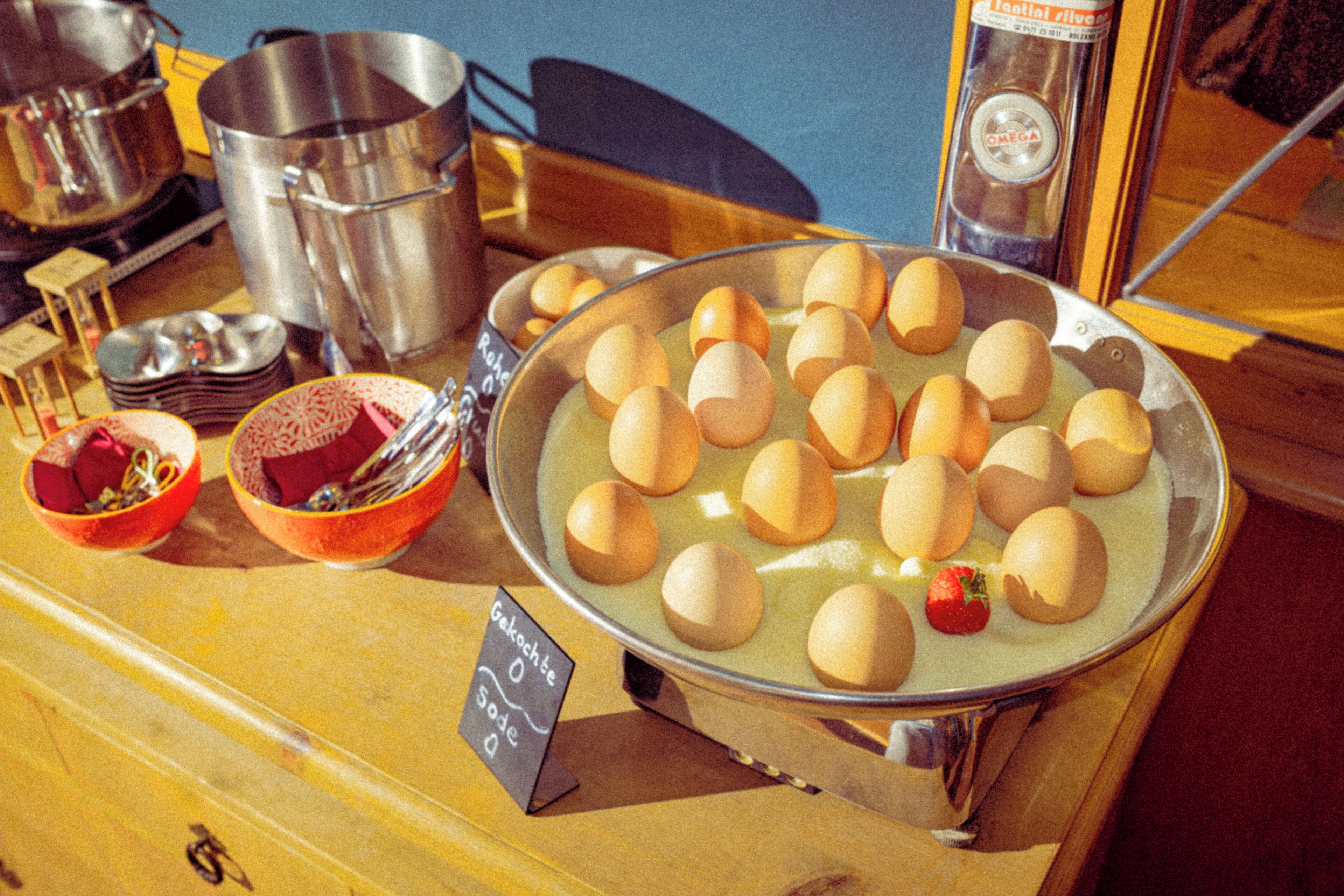 Een dienblad met ronde, goudbruine items, mogelijk voedsel, op een houten tafel met metalen bakken en een bordje waarop de prijs 0 staat.