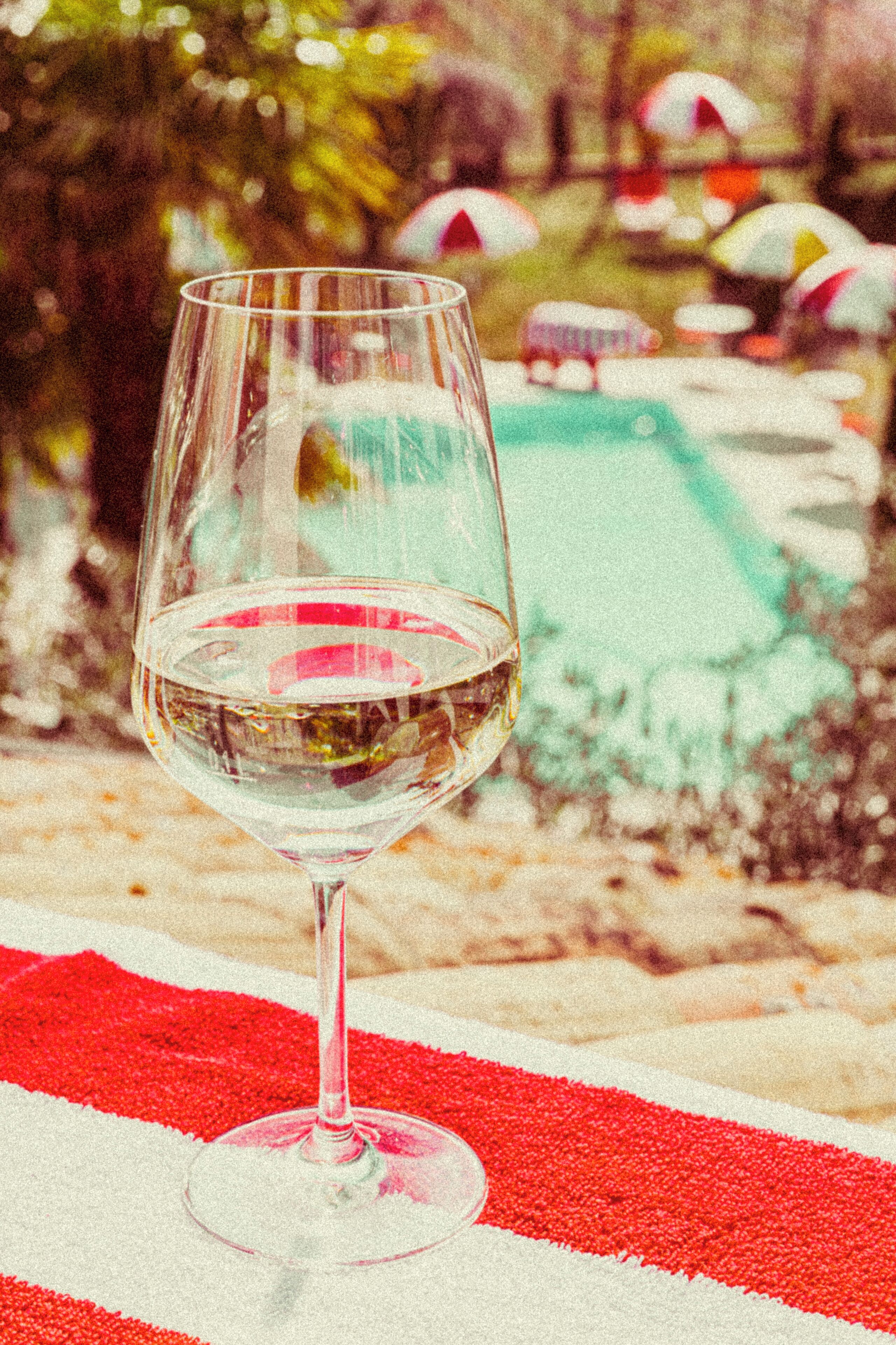 A glass of white wine on a red and white striped tablecloth.