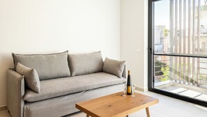 A modern living room with a grey sofa, a wooden coffee table, and a bottle of wine. - Grec Suites Dafni, Athens by GrecCollection President Suite (Dafni)