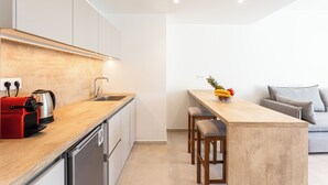 A modern kitchen with a wooden countertop, stainless steel appliances, and a built-in island with bar stools. - Grec Suites Dafni, Athens by GrecCollection President Suite (Dafni)