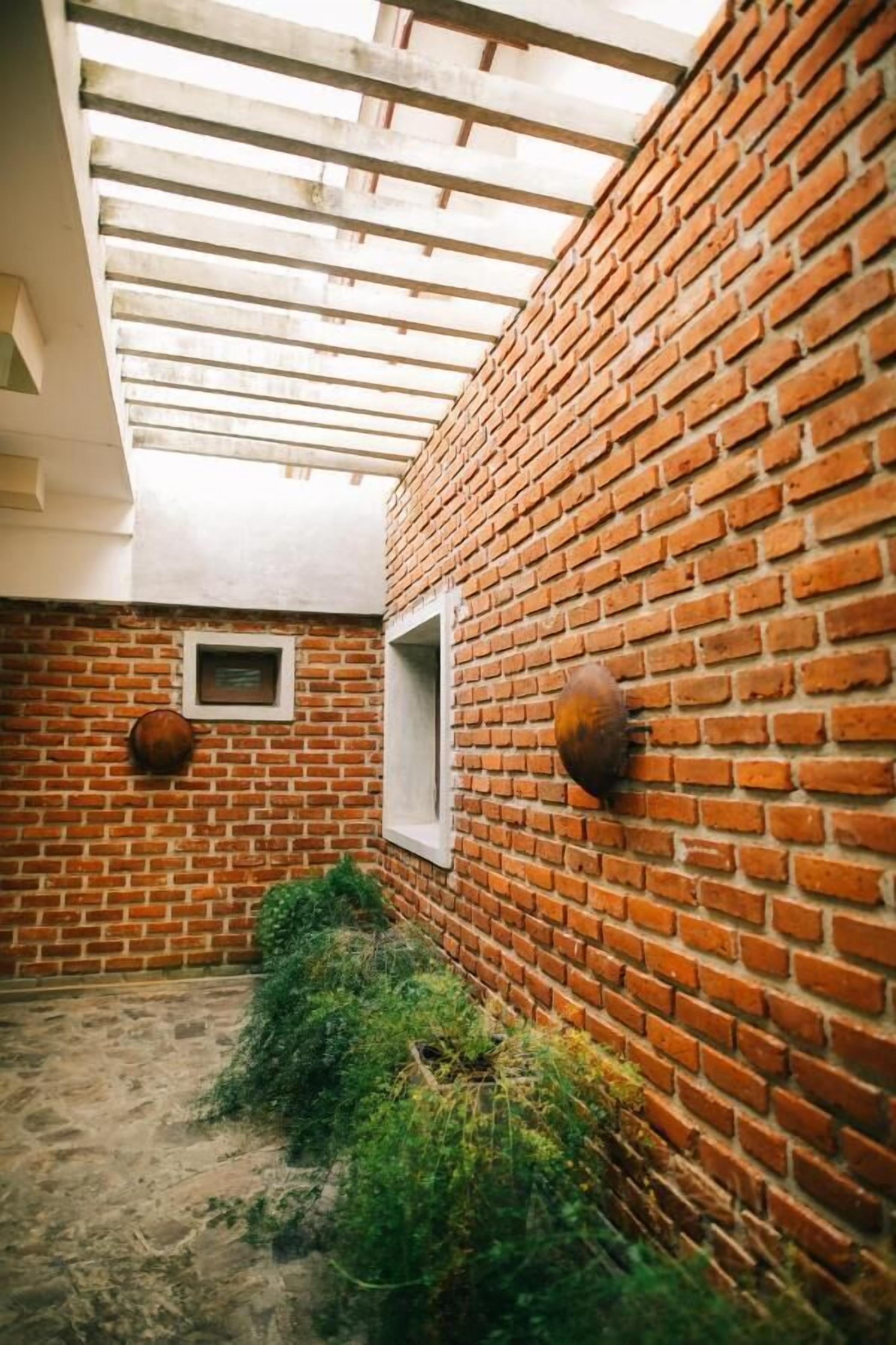 Un patio con paredes de ladrillo, techo de madera, una pequeña ventana y un objeto colgado en la pared.
