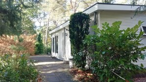 A single-story house with a front porch, a small attached garage, and a well-maintained garden. - Lovely vacation home on beautiful park (Diever)