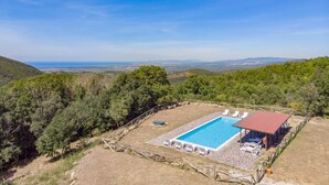A swimming pool with lounge chairs and a covered seating area, surrounded by hills and trees. - 2 bedroom amazing home in Sassetta (Sassetta)