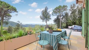 A patio with a table and chairs, overlooking a scenic landscape with trees and hills. - 2 bedroom amazing home in Sassetta (Sassetta)