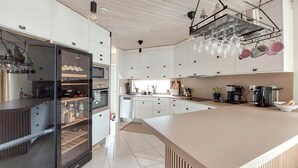 A modern kitchen with white cabinets, a large island, and a wine rack.