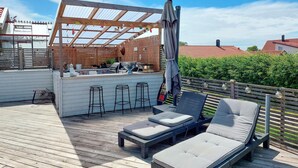 A wooden deck with lounge chairs and a bar area.