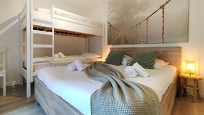 Une chambre avec un lit superposé, une table de chevet avec une lampe et une œuvre d’art accrochée au mur.