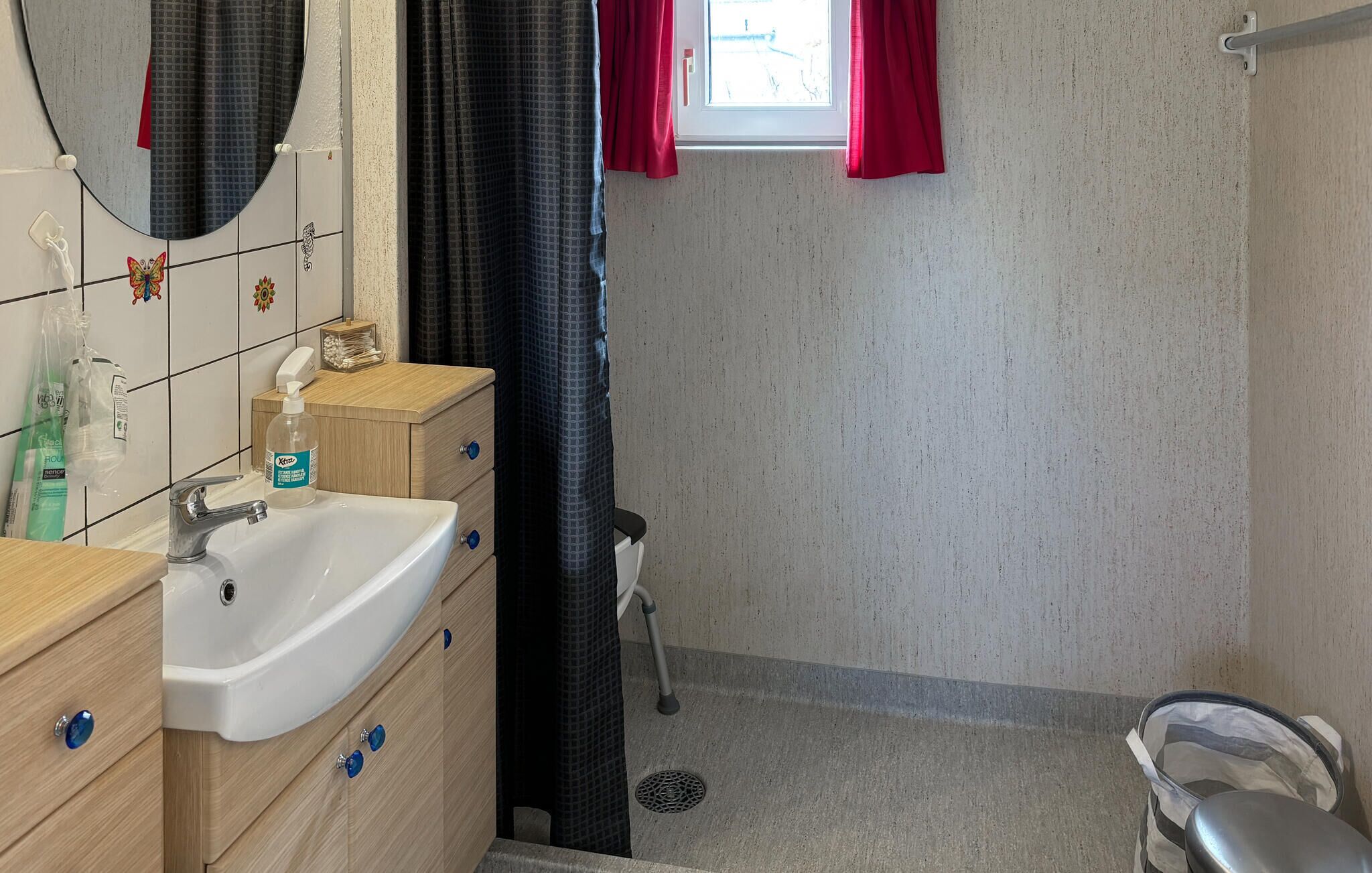 Een badkamer met een wit wastafel, houten kastjes, een spiegel en een douchehoek.