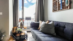 Una sala de estar moderna con un sofá gris, una mesa de centro con objetos decorativos y vistas por un ventanal grande.