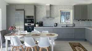 Een moderne keuken met grijze kastjes, een ingebouwde oven, een roestvrijstalen afzuigkap en een raam met uitzicht.