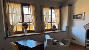 Una habitación con una mesa de madera, un sofá blanco y una ventana con cortinas.