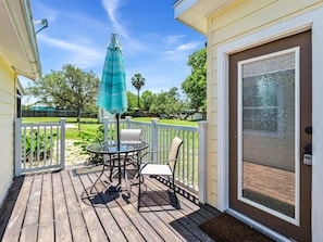 Enjoy a peaceful moment on this deck with a glass table and two chairs, surrounded by lush greenery.