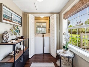Convenient laundry facilities with two washing machines and dryers, a bench, and a small table.