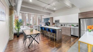 A modern kitchen with a central island, stainless steel appliances, and a dining area with a wooden table and chairs.