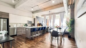 A modern kitchen with a central island, bar stools, and a dining area with a table and chairs.