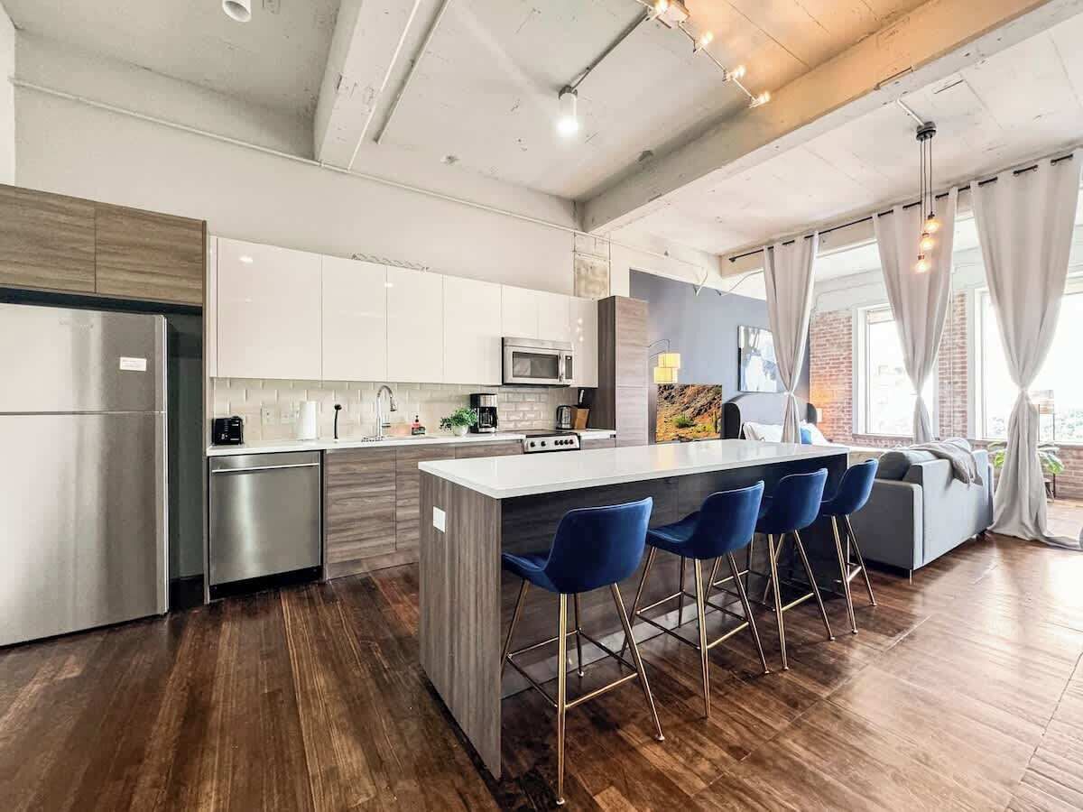 Een moderne keuken met een centraal eiland, barstoelen en een zithoek met een bank.