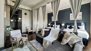 Ein modernes Hotelzimmer mit einem großen Bett, einer Couch, einem Glastisch und einem kleinen Tisch mit einer Vase.