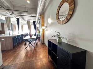 A modern interior with a dining area, wooden flooring, a black console, and a round mirror on the wall.