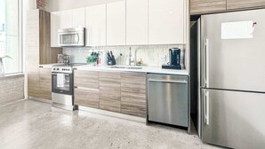 A modern kitchen with stainless steel appliances, white cabinetry, and a large window. - Elegant 2BD | DT Dallas | Sleeps 5 | ValetParking (Dallas)