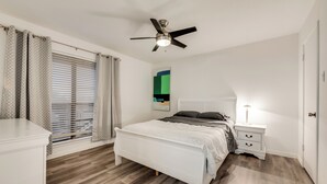 A bedroom with a white bed, a nightstand, a ceiling fan, and a window with blinds. - 2-bedroom condo in charming Dallas with WiFi, AC (Dallas)