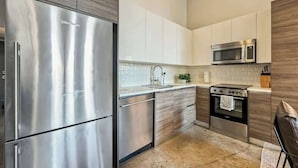 Une cuisine moderne dotée d’appareils électroménagers en acier inoxydable, de meubles blancs et d’un mur d’accent en bois.