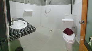 A bathroom with a white sink, a toilet, and a shower. - Athome Hotel Nanai 8 (Patong)