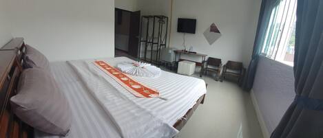 A hotel room with a bed, a desk, a chair, and a TV.