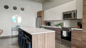 Una cocina moderna con una isla central, electrodomésticos de acero inoxidable y una pared de acento de madera.