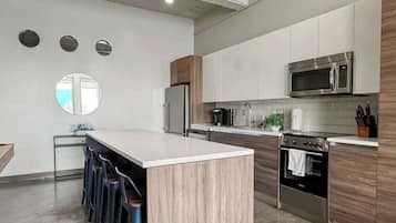 A modern kitchen with a central island, stainless steel appliances, and a wooden accent wall.